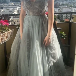 Balklänning / Studentklänning  - Superfin klänning i tyll, jadegrön -ljusgrå melerad med fantastiska detaljer. Endast använd 1 gång, nypris 7500kr, köpt på SE Fashion i Södertälje. 