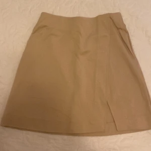 Kort beige kjol - Säljer denna fina kjolen med en liten slit på ena sidan då den inte passar mig, köpte den men orkade inte lämmna tillbaka och har sen dess inte kommit till vidare användning. Den är från HM, helt ny, prislappen sitter kvar, och nypriset är 150 kr💓