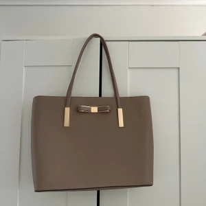 Handväska - Beige handväska med guld detaljer. Iprincip oanvänd och i mycket gott skick. Köparen står för frakten! 