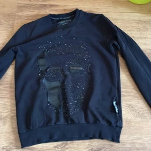 Philip plein hoodie/sweatshirt - Hej, Philip plein sweatshirt osäker på äkthet men tror kop1a diamanter/kristaller har lossnat och vissa lossnar fof litet hål men som går att laga enkelt om man vill det annars använd i bra skick postar så fort det går efter du köpt varan skick 7/10