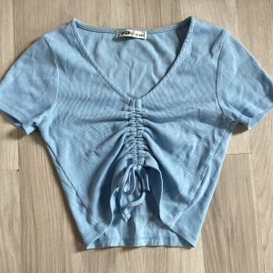 Blå T-shirt  -  Jättegullig ljus blå topp som är v ringad och  har snörning som kan knyter til en lite rosett💗 Super skick!