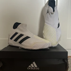 Padel/Tennis skor från Adidas - Helt orörda! Blev fel storlek vid köp. Kartongen har sett ljusare dagar men skorna är hela och rena, ingår även ett skohorn som går ner i väskan!