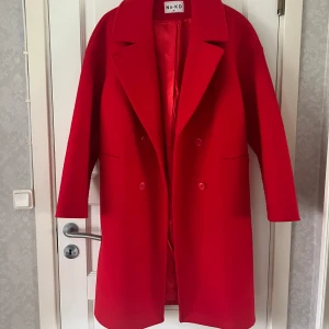 Röd kappa - Jättefin röd kappa från NA-KD i storlek 36 men passar även större storlekar beroende på hur man vill ha passformen. Något nopprig på framsidan men annars fin kvalitet. Köparen står för frakten. 