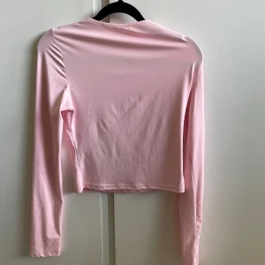 Rosa Långamrad topp - Säljer denna snygga topp i typ tränings material från SHEIN, säljer pgr lite liten i armarna. Säljer allat jag säljer för 20kr för 150kr tillsammans. Pris kan diskuteras💗