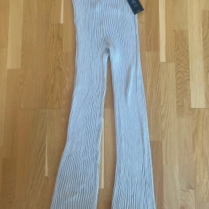 Nya beiga stickade ribbade byxor från NA-KD strl M - Nya beiga stickade ribbade byxor från NA-KD strl M.  Modell: Ribbed knitted pants  Den sista bilderna är lånade från NA-KDs hemsida  Nya, med prislappen kvar   Mått Midjan: ca 33 cm Längd från grenen och ner: ca 86 cm  89% viskos och 11% polyamid 