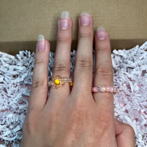 2-pack ringar  - 2 stycken rosa/genomskinliga ringar, en av de har blommor på sig.