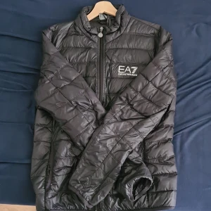 Ea7 sommarjacka - En svart armani sommar jacka i storlek L som skulle passa till M också. Den har ett hål som är patchad och syns minimalt vid armbågen. Till jackan får man också armani påsen som man kan lögga jackan i. Priset är diskuterbart!