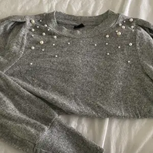 En långärmad, grå tröja med pärlor 