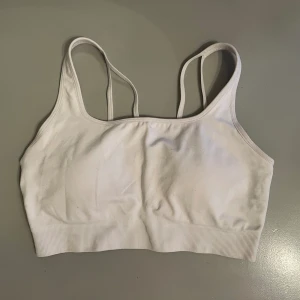 Vit träningstopp - Säljer denna fina topp från NVGTN i storlek S!  Sparsamt använd, fint skick.  Köpt för 335 kr.  Skriv för fler bilder🫶🏻