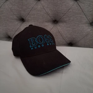 Hugo Boss keps - Svart Hugo Boss kepes med ljusblåa detaljer. Hugo Boss finns ej kvar och säljs ej längre.
