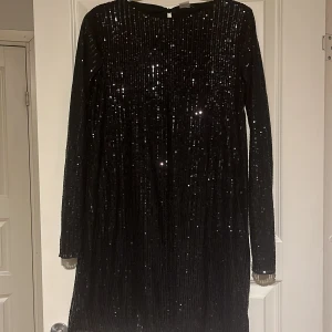 Kort svart långärmad paljett klänning - Jag säljer nu min fina paljettklänning som är i nyskick då den endast är använd en gång. Köpt på Lindex barnavdelning, men passar mig som brukar ha S/M från damavdelningen. Pris går att diskuteras vid snabb affär! Skriv gärna privat för fler bilder🩷