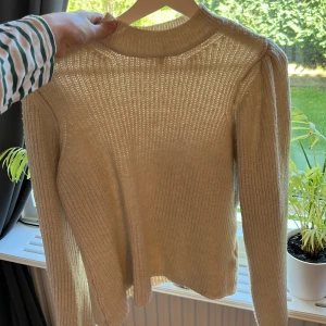Stickad tröja från Nelly - Beige stickad med lite puffiga axlar, fint skick och jätte skön