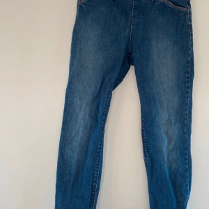 Blå jeans med dragkedja - Ett par blå jeans med dragkedja vid bensluten. Jeansen har en klassisk design med fickor fram och bak samt en knapp och dragkedja i midjan.