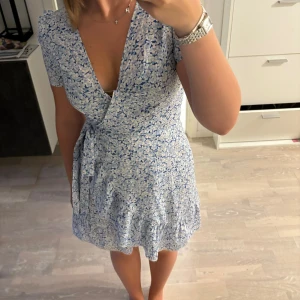 Blå och vit blommig klänning - En blå och vit blommig klänning, den har använts men har inga skador eller fläckar, köparen står för frakten