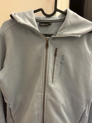  Sail Racing Zip hoodie - Baby blueZip hoodie från Sail Racing med hel dragkedja och broderad logga på bröstet och huvan. Utsidan är mjuk och insidan har fleece. Tröjan har huva, sidofickor och en extra bröstficka med dragkedja. Materialet är 80% bomull och 20% polyester. Nypris 1500kr Pris kan justeras något vid snabb affär !