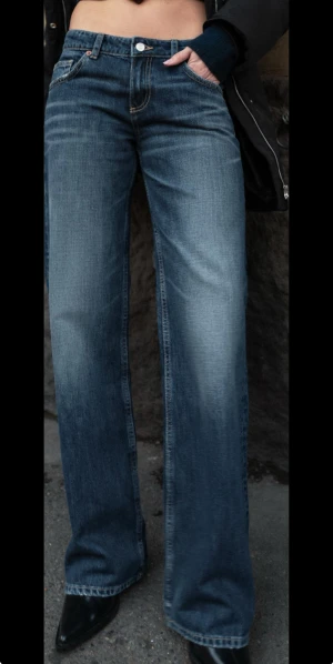 Blå wide jeans med låg midja - Snygga blå jeans med låg midja och breda ben, klassisk femficksmodell med kontrastsömmar. Jeansen har en mörk tvätt med lätt slitning och är tillverkade i jeansmaterial. Perfekta för dig som gillar en avslappnad och trendig look.