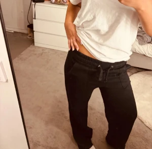 Svarta mjukisbyxor med snörning - Svarta mjukisbyxor med avslappnad passform och snörning i midjan. Byxorna har sidofickor och är tillverkade i mjukt material som är perfekt för chill dagar. Passar dig som gillar en loose och bekväm stil.