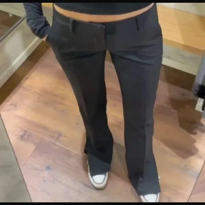 Svarta bootcut kostymbyxor Lågmidjade  - Snygga svarta kostymbyxor med bootcut passform och klassisk midja. Byxorna har fickor fram och stängs med dragkedja och knapp. Perfekta för en clean och stilren look, passar till sneakers eller boots. Är i samma modell som på bilden, slits ned till, Lågmidjade! Modellen Vera, använt 4 gånger, inte mer. 