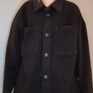 Svart kappa - Använd men i bra skick.  Hund och katt tillkommer I hemmet, kappan tvättas innan den skickas. Skickas via instabox/ postnord. 