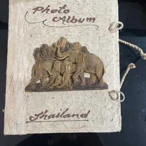 Photo Album Thailand - Unikt fotoalbum med handgjord känsla och vackert elefantmotiv från Thailand. Perfekt för att samla dina bästa minnen och ge en exotisk touch till din samling. Omslaget är dekorerat med snidade elefanter och naturmotiv – en riktig blickfångare för unga äventyrare!