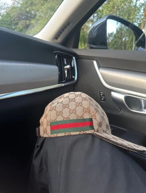 Gucci beige keps med GG-mönster - Säljer en snygg beige keps från Gucci med klassiskt GG-mönster över hela kepsen. Den har en böjd skärm och justerbar rem baktill. På sidan finns den ikoniska gröna och röda randen. Materialet är slitstark bomullscanvas med bruna detaljer.