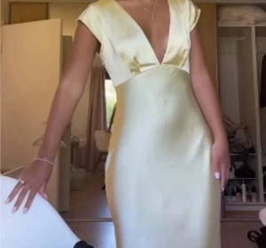 Ljusgul långklänning med djup v-ringning - Säljer en elegant ljusgul långklänning i satin. Klänningen har korta ärmar och en djup v-ringning framtill som ger en snygg och modern look. Perfekt till balen eller finare tillfällen! Aldrig använd 🥰