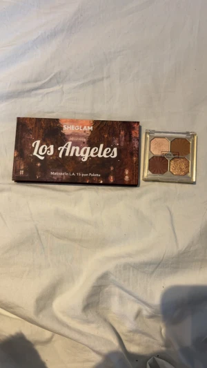 Ögonskuggspaletter SHEGLAM & Sence - Säljer två ögonskuggspaletter: SHEGLAM Los Angeles med 15 nyanser i matta, skimrande och glittriga toner som beige, guld, brunt och svart. Sence-paletten har 5 skuggor i nude, koppar, guld och brunt med både matt och glittrig finish. Perfekt för kreativa looks!
