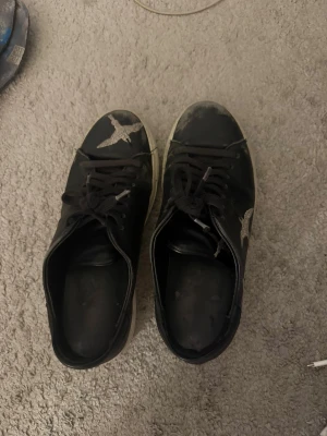 Svarta Axel Arigato sneakers med fågelbrodyr - Svarta sneakers från Axel Arigato med broderade silvriga fåglar på sidorna. 