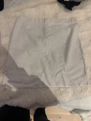 Vit glittrig kortkjol från Zara - Supersnygg vit kortkjol från Zara med glittriga paljetter över hela tyget. Kjolen har en rak och tight passform som sitter snyggt på kroppen. Materialet är mjukt och stretchigt för skön känsla.