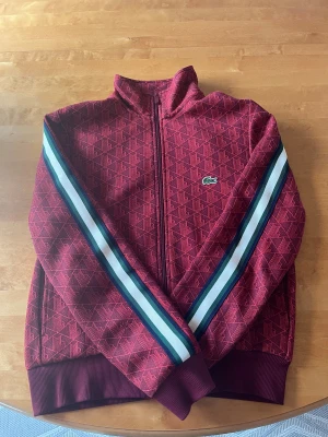 Lacoste Monogram zip - En ovanlig vinröd lacoste monogram zip i storlek S, Köpt på Zalando. Äktahetsbevis finns i form av digitalt kvitto. Färgen är en av de som slutade tillverkas och färgen är därför ovanlig. Väldigt sparsamt använd och har till och med hållts borta från regn med mera, ser ut precis som ny! Resell värdet ligger på omkring 3000kr. Tveka inte på att höra av er vid frågor och intresse!