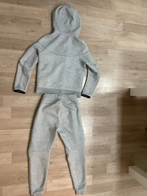 Grå Nike hoodie i mjuk bomull - Säljer en grå hoodie från Nike i mjuk bomullsblandning. Tröjan har huva, långa ärmar och svarta detaljer vid ärmslut. Perfekt för chill eller träning. Klassisk Nike-logga på bröstet och bekväm passform.