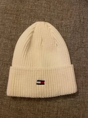 Vit ribbad mössa Tommy Hilfiger - Säljer en helt ny Tommy Hilfiger mössa! Aldrig använd utan testad en gång!  Säljes då den inte var något för mig och jag tyckte den kändes trång💗