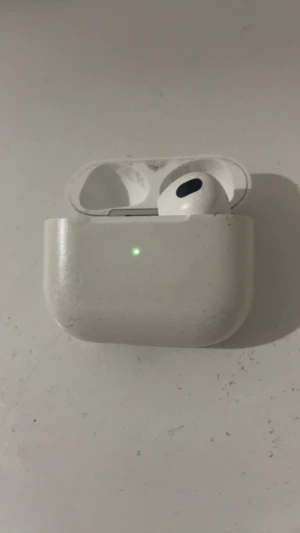 AirPods 3 - Apple AirPods 3 med laddningsetui. Endast en hörlur ingår. Skalet och hörluren har tydligt yttre slitage och repor, men laddningsindikatorn fungerar. Perfekt för dig som behöver reservdelar eller en extra hörlur.