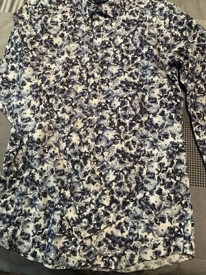 Blommig skjorta från Sand Copenhagen - Säljer en snygg skjorta från Sand Copenhagen med blommigt mönster i mörkblå och vita toner. Skjortan har klassisk krage, knappar framtill och långärmade ärmar. Perfekt för dig som gillar att sticka ut med coola prints och stilren design.