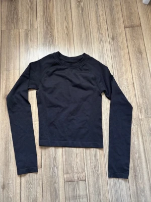 Svart långärmad topp - En enkel svart långärmad topp med rund hals. Materialet känns mjukt och stretchigt, perfekt för att matcha med jeans eller kjol. Stilren design utan synliga detaljer eller mönster, passar dig som gillar minimalistiskt.