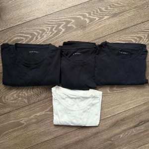 Marinblå och vit t-shirt från Pier One - Fyra svarta och en vit t-shirt från Pier One. Alla har rund hals och är kortärmade, tillverkade i mjuk bomull. Perfekt för en clean och enkel stil, lätt att matcha med jeans eller shorts. Snygga basplagg som funkar året runt.