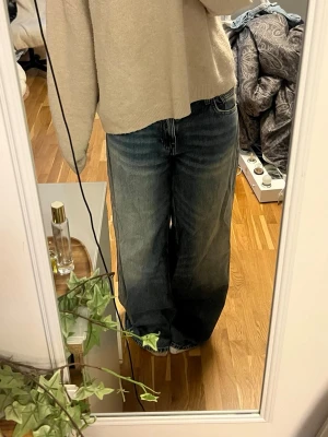 Wide jeans från Bershka - Säljer ett par blå jeans från Bershka i storlek EUR 36. Modellen har breda ben och klassisk femficksdesign. Jeansen är tillverkade i denim och har en cool, lite tvättad look med ljusare partier. Perfekt för dig som gillar loose och avslappnad stil.