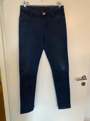 Mörkblå skinny jeans från Honey Bblue - Snygga mörkblå jeans från Honey Bblue i skinny fit med klassisk femficksdesign. Byxorna har hög midja och är tillverkade av 74% bomull, 22% polyester och 4% elastan för en skön stretch. Perfekt för dig som gillar en smal siluett och stilren look. Passar bra till stövlar. 