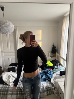 Svart långärmad croppad topp H&M - En svart långärmad croppad topp från H&M. Enkel och stilren design med rund halsringning och tight passform. Perfekt att matcha med jeans eller kjol för en clean look.