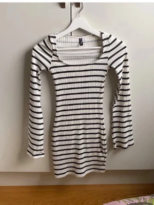 Randig ribbad kortklänning Gina Tricot - Säljer en vit och svart ribbad kortklänning från H&M med långärmade ärmar och rundad hals. Klänningen har ett stilrent randigt mönster och är figurnära i passformen. Perfekt för dig som gillar enkel men snygg design.