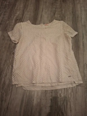 Vit blus med spetsdetaljer - Säljer en vit blus från dobber med korta ärmar och rund hals. Blusen har ett spetsmönster över hela plagget och ett extra lager tyg undertill. Blusen är i fint skick och har andvändts få tal gånger. Storlek M men passar som en S, loose fit. Köptes för ca 500 kr, priset kan förhandlas!