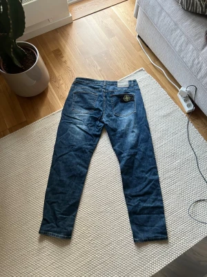 Blå jeans från Stone Island - Säljer ett par blå jeans från Stone Island med klassisk patch på bakfickan. Jeansen har raka ben, normal passform med lite stretch.  OBS DU VET VARFÖR DE ÄR BILLIGA!
