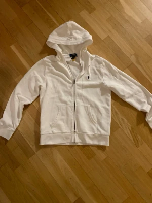 Ralph Lauren zip up - Säljer en vit Ralph lauren zip up hoodie som var köpt för 1295kr💕 Finns några små fläckar på ärmen som knappt syns när man har på sig den, därav det låga priset💕 bara att fråga om ni vill ha fler bilder