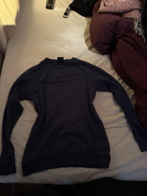 Mörkblå Peak Performance tröja - Säljer en mörkblå långärmad tröja från Peak Performance med tryckt logga på bröstet. Tröjan har rund hals och ribbade muddar vid ärmslut och nederkant. Perfekt för dig som gillar stilrena och sportiga plagg.