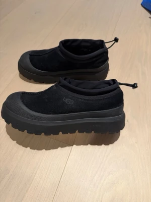UGG Tasman Slip-In | Strl 43 | Som nya - VINTERSKOR! Säljer ett par svarta UGG slip-ins i storlek 43. Köpta från Zalando i december 2024.  Använda endast ett fåtal gånger, i mycket fint skick. Inga skador eller fläckar, se bilder!  Otroligt bekväma, varma och enkla att ta på – perfekta höst och vinterskon som kombinerar stil och funktion!  ✔️ Rena och väl omhändertagna ✔️ Borstade efter varje användning ✔️ Förvarade med skoblock både mellan användningar och vid sommarförvaring  Storlek: 43 Färg: Svart Märke: UGG Nypris: 2 400 kr