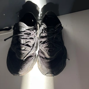 Svarta Adidas sneakers strl 36 - Säljer ett par svarta Adidas sneakers med chunky sula och meshdetaljer. Skorna har snörning och en rund tå, samt en platt sula med mönstrad undersida. Perfekta för dig som gillar sportig stil och vill ha bekväma skor till vardagen.