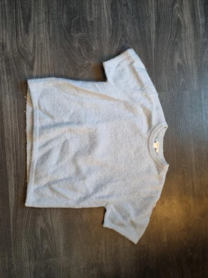 Ljusblå stickad tröja Gina Tricot - Supermjuk ljusblå stickad tröja från Gina Tricot med korta ärmar och rund halsringning. Perfekt för lager-på-lager och/enkel att matcha med jeans eller kjol. Tröjan har en avslappnad passform och ribbade detaljer vid halsen.