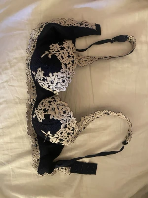 Intimissimi BH - Säljer en blå bh från intimissimi med vacker spets och blommigt mönster i vit. BH har vadderade kupor och fina spetsdetaljer.