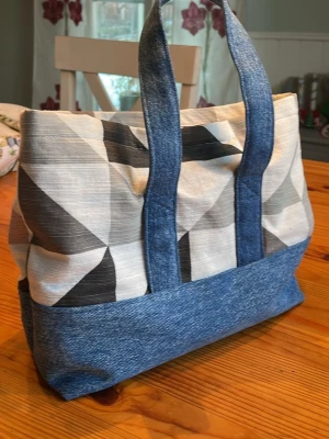 Nysydd väska - återbruk - Läckert tyg med geometriskt mönster i kombination med denim.  Fodrad med enfärgat mörkblått tyg.  Två ”flärpar” så man kan stänga igen lite (med kardborre).  Se mått på sista bilderna.  Egen tillverkning. Endast detta exemplar. 
