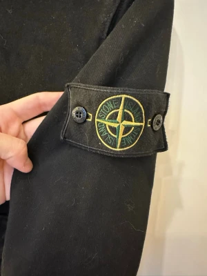 Svart huvtröja Small - Köpt utomlands ser ut som Stone Island   Svart hoodie med avtagbart märke på vänster ärm. Klassisk modell med ficka fram.